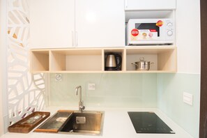 A kitchen with a microwave, a kettle, and a sink.