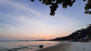 A beach with a calm sea, sandy shore, and a clear sky. - Runa  Runa Guesthouse (Rayong)