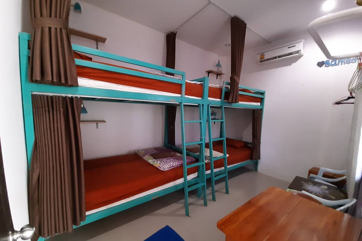 A bunk bed room with a wooden table and a hanging light fixture.