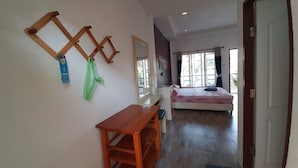 A hotel room with a bed, a desk, and a chair. There is a window with curtains, and a door leading to the outside. - Runa  Runa Guesthouse (Rayong)
