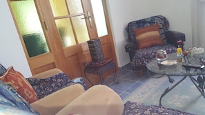 A cozy living room with a sofa, armchair, and a small table with decorative items.