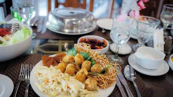 Una mesa de comedor dispuesta con un plato de pasta, albóndigas y fideos, rodeada de varios platos y utensilios.