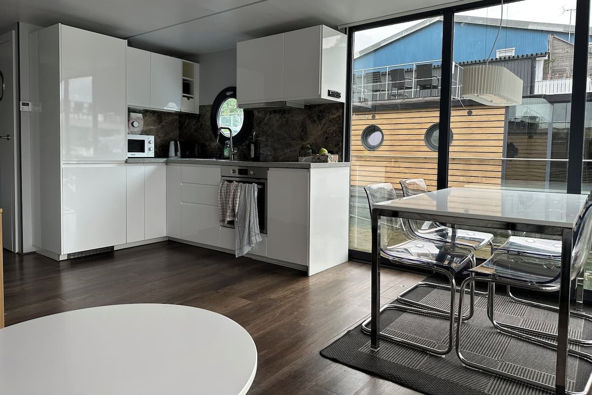 A modern kitchen with white cabinets, a built-in oven, and a large window.