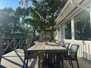 An outdoor deck with a wooden table and chairs, surrounded by trees and a railing. - La Mare Resort (Gothenburg)