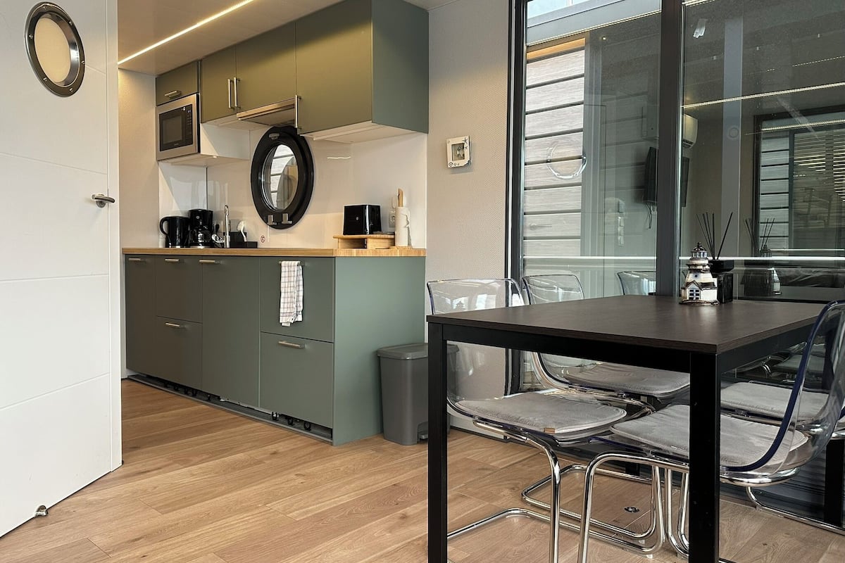 A modern kitchen with a microwave, coffee maker, and a round mirror on the wall.
