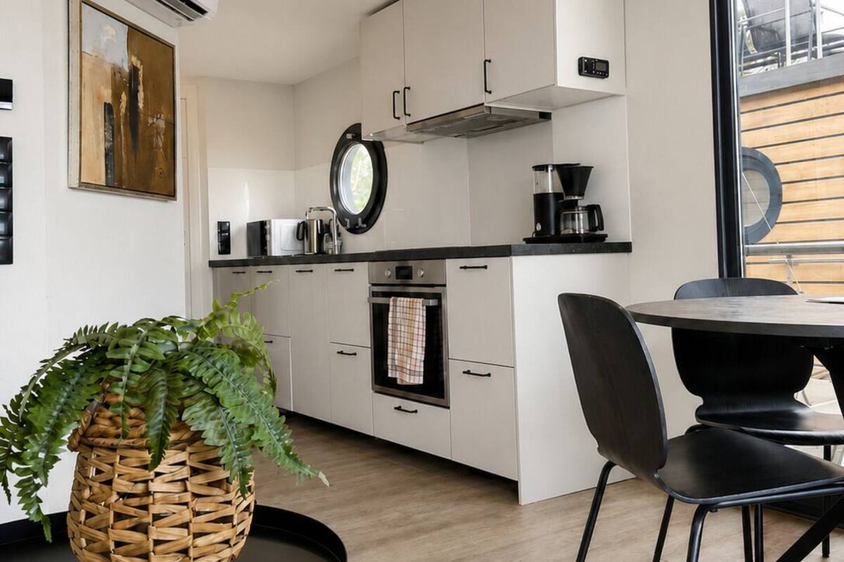A modern kitchen with white cabinets, a round dining table, and a large window.