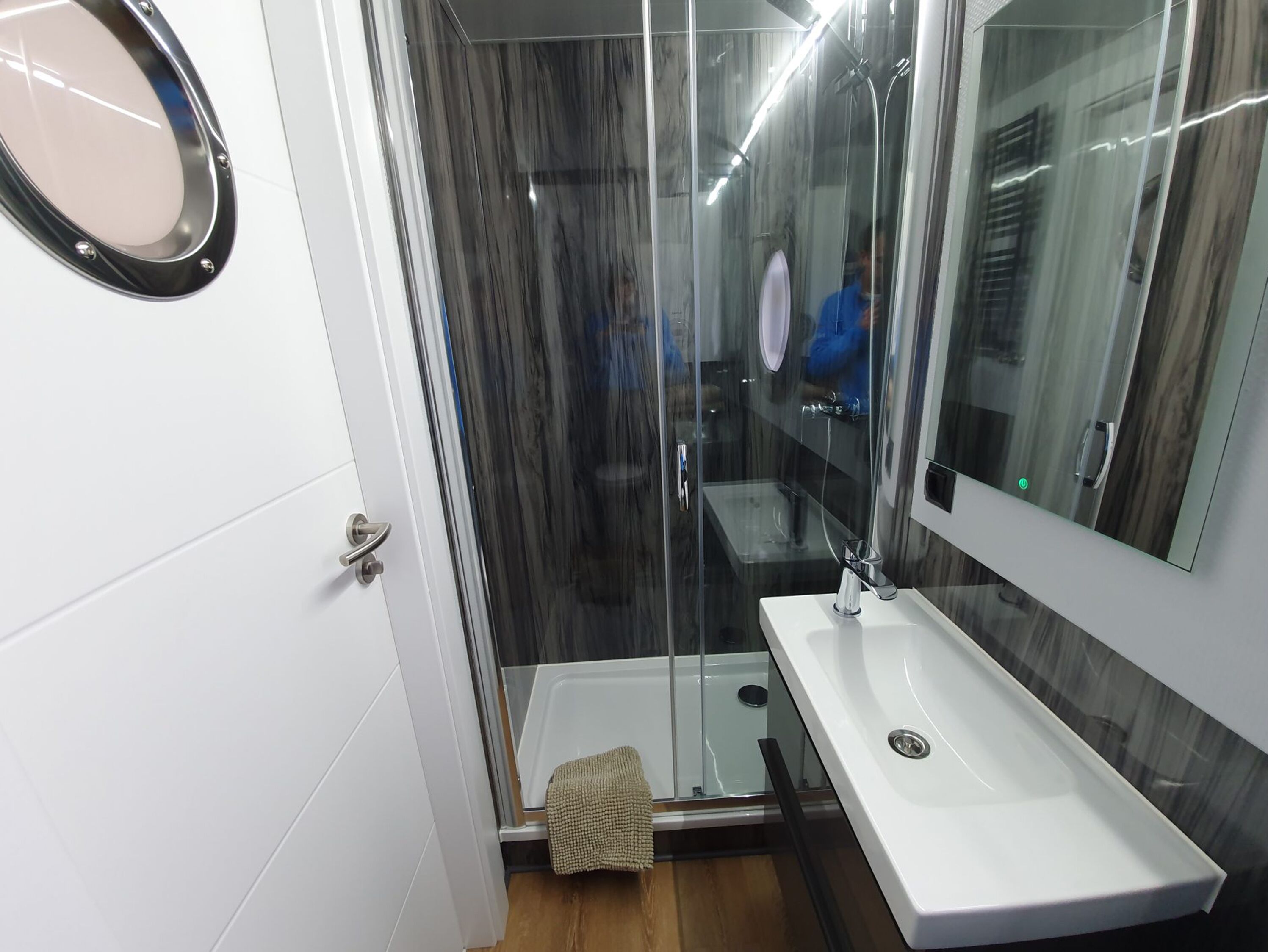 A modern bathroom with a glass-enclosed shower, a white sink, and a large mirror.
