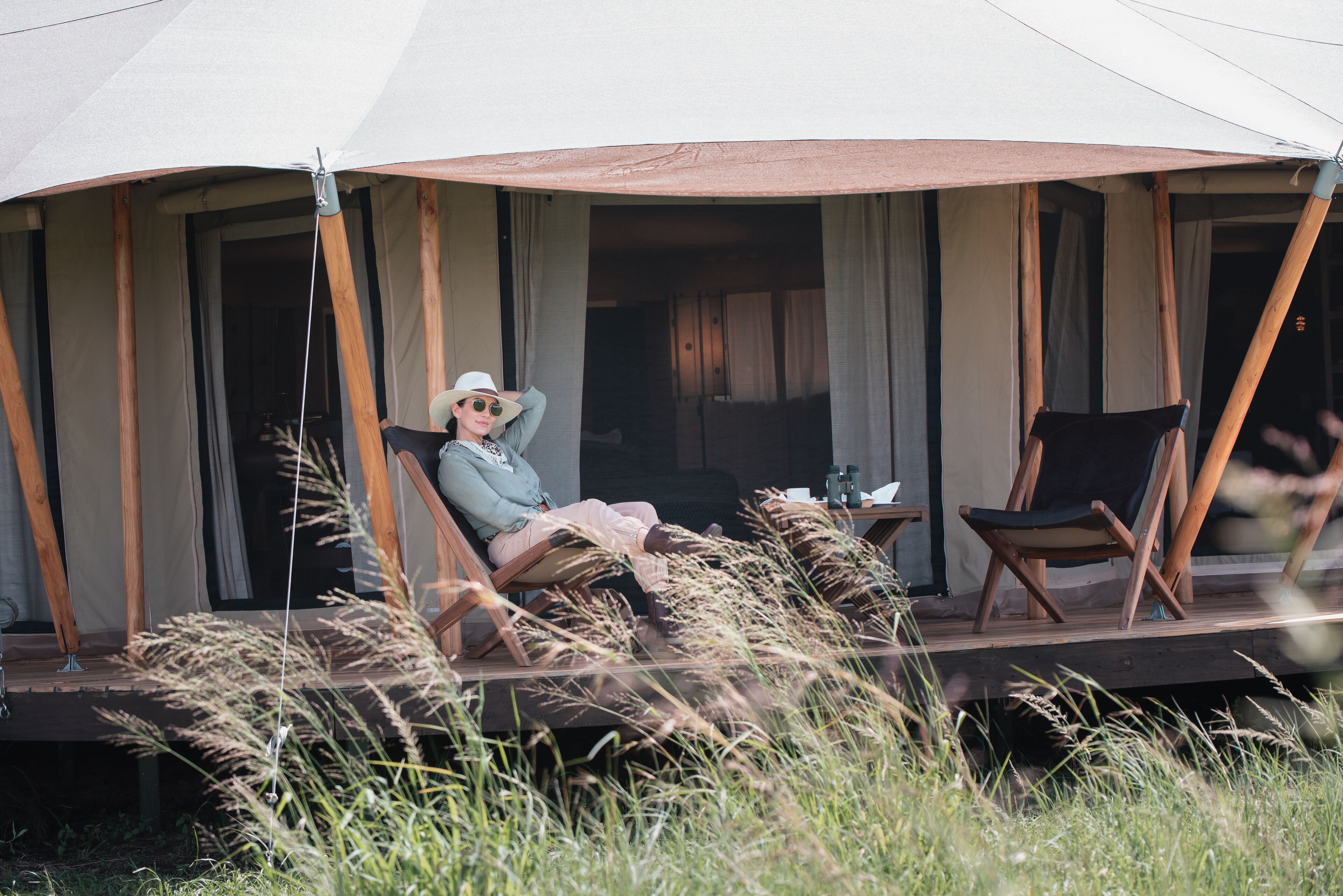 A tented outdoor area with a person relaxing on a lounge chair.