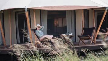 A tented outdoor area with a person relaxing on a lounge chair.