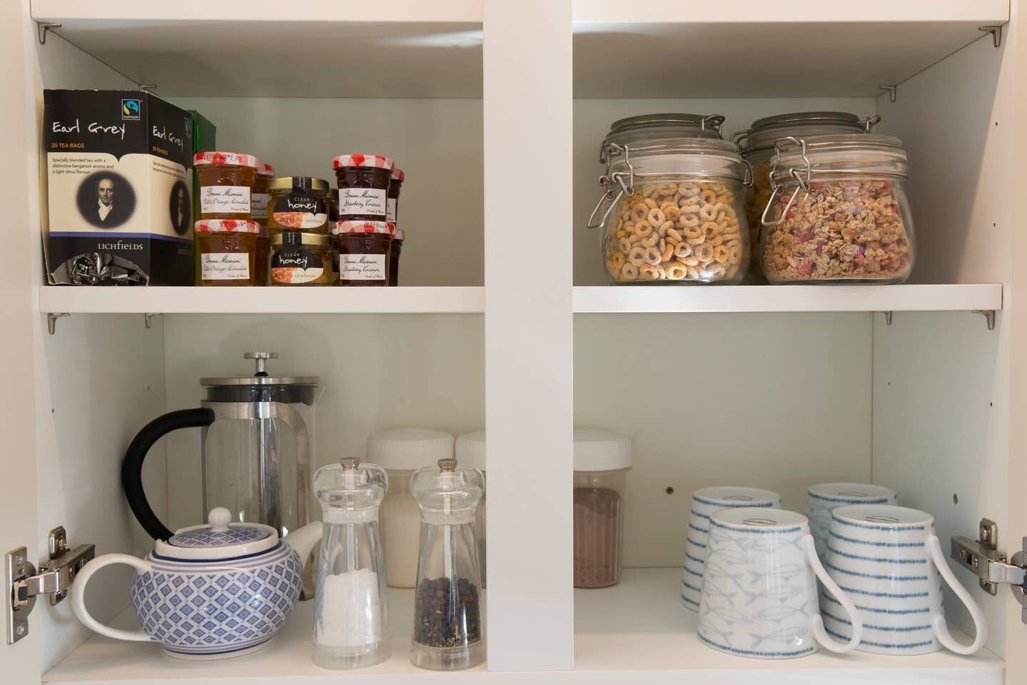 Un garde-manger contenant des sachets de thé, des pots de miel, des céréales et des épices.