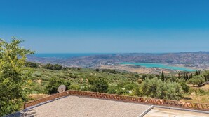 A terrace with a view of a coastal landscape, including a turquoise lake and distant hills. - Lovely home in Periana (Periana)