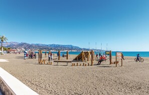 A beach with a volleyball net and wooden structures, a cyclist, and mountains in the background. - Lovely home in Periana (Periana)