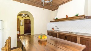 A kitchen with a wooden table, a sink, and cabinets. There is a fruit basket on the table. - Lovely home in Periana (Periana)