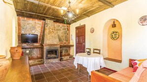 A cozy room with a stone fireplace, a television, and a dining table. - Lovely home in Periana (Periana)
