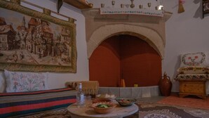 A traditional room with a stone fireplace, a large tapestry, and a patterned rug.
