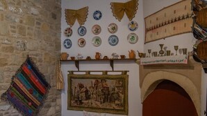 A cozy room with a stone wall, a fireplace, and various decorative plates and textiles.