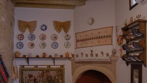 A cozy living room with a fireplace, patterned rugs, and a variety of decorative plates and pottery on the walls.