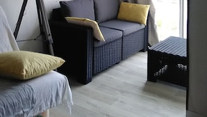 Ett modernt vardagsrum med en soffa, en lampa och utsikt över staden genom ett stort fönster.