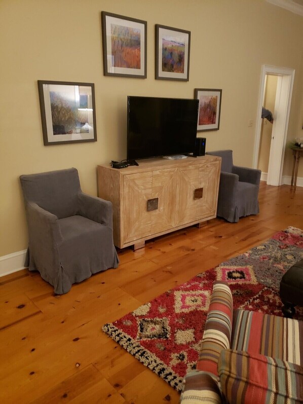 A living room with a wooden entertainment center, a flat-screen TV, and a patterned rug. - Darby's Guest House! (Natchez)