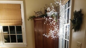 A room with wooden flooring, a wooden cabinet, a small table, and a window with blinds. - Darby's Guest House! (Natchez)