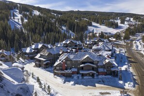 A snow-covered mountain town with wooden buildings and a ski slope in the background.