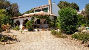 Una villa de estilo mediterráneo con techo de tejas, ventanas arqueadas y camino de entrada de grava.