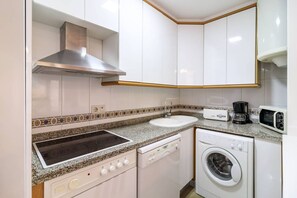 Enjoy cooking in this well-equipped kitchen with a granite countertop, stainless steel range hood, dishwasher, and front-loading washing machine.