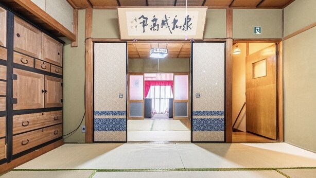 A traditional Japanese room with tatami flooring, a wooden wardrobe, and a sliding door leading to another room.