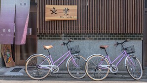 A purple bicycle parked in front of a building with a wooden sign above it.