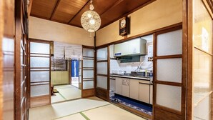 A traditional Japanese-style room with tatami flooring, a wooden ceiling, and sliding doors.
