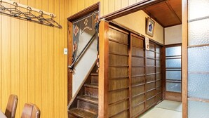 A traditional Japanese room with tatami flooring, a wooden staircase, and sliding doors.