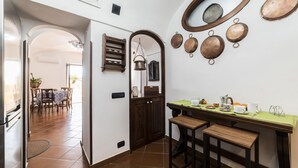 A kitchen with a wooden table, stools, and a hanging pot rack.