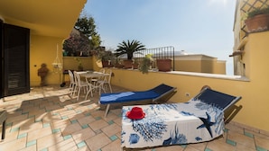 A sunlit patio with a table, chairs, and two lounge chairs.