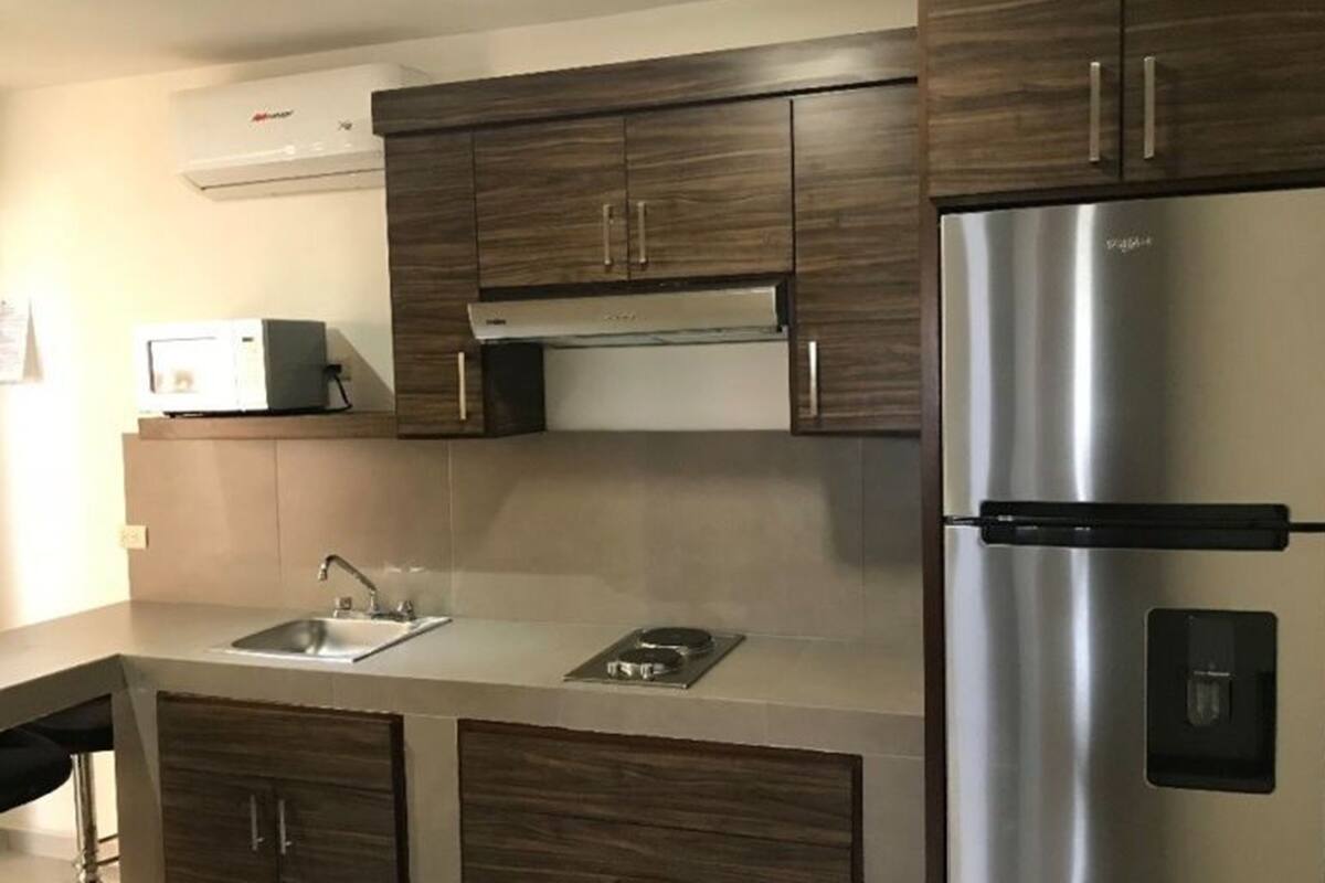 A modern kitchen with dark wood cabinets, stainless steel appliances, and a built-in microwave.