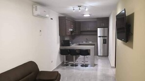 A modern kitchen with a central island, bar stools, and a built-in refrigerator.