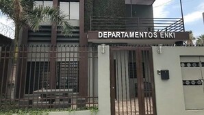 A building with a sign reading "DEPARTAMENTOS ENKI" and a gated entrance.