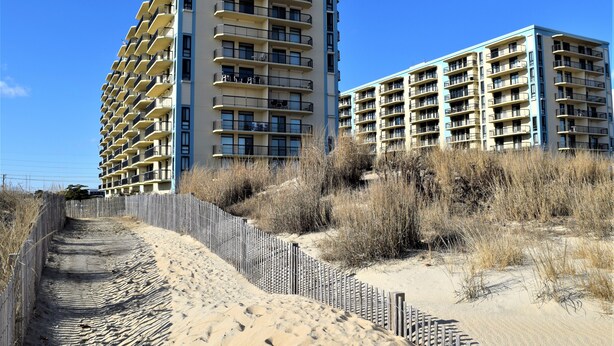A beachfront hotel with multiple balconies and a sandy walkway leading to the beach. - LINENS & DAILY ACTIVITIES INCLUDED! Braemar -1BR - Pool, Tennis & Fitness Center (Ocean City)