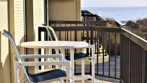 A balcony with a white table and chairs, overlooking the ocean. - LINENS & DAILY ACTIVITIES INCLUDED! Braemar -1BR - Pool, Tennis & Fitness Center (Ocean City)
