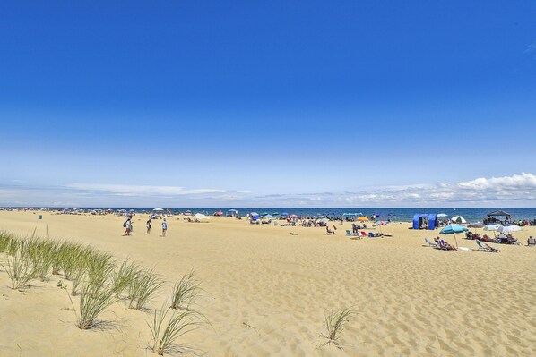 A sandy beach with people, umbrellas, and tents.