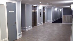 A hallway with grey walls, white trim, and a tiled floor. There are doors on the left labeled 'TRASH DISPOSAL ROOM' and 'EXIT.' - LINENS & DAILY ACTIVITIES INCLUDED! Braemar -1BR - Pool, Tennis & Fitness Center (Ocean City)