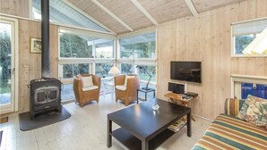 A cozy living room with a large window, a fireplace, wicker chairs, a sofa, and a TV. - Cozy home in Blokhus with WiFi (Blokhus)