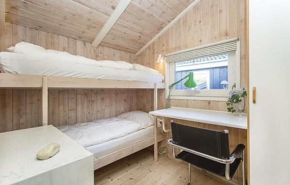 A bunk bed room with a desk and a window.