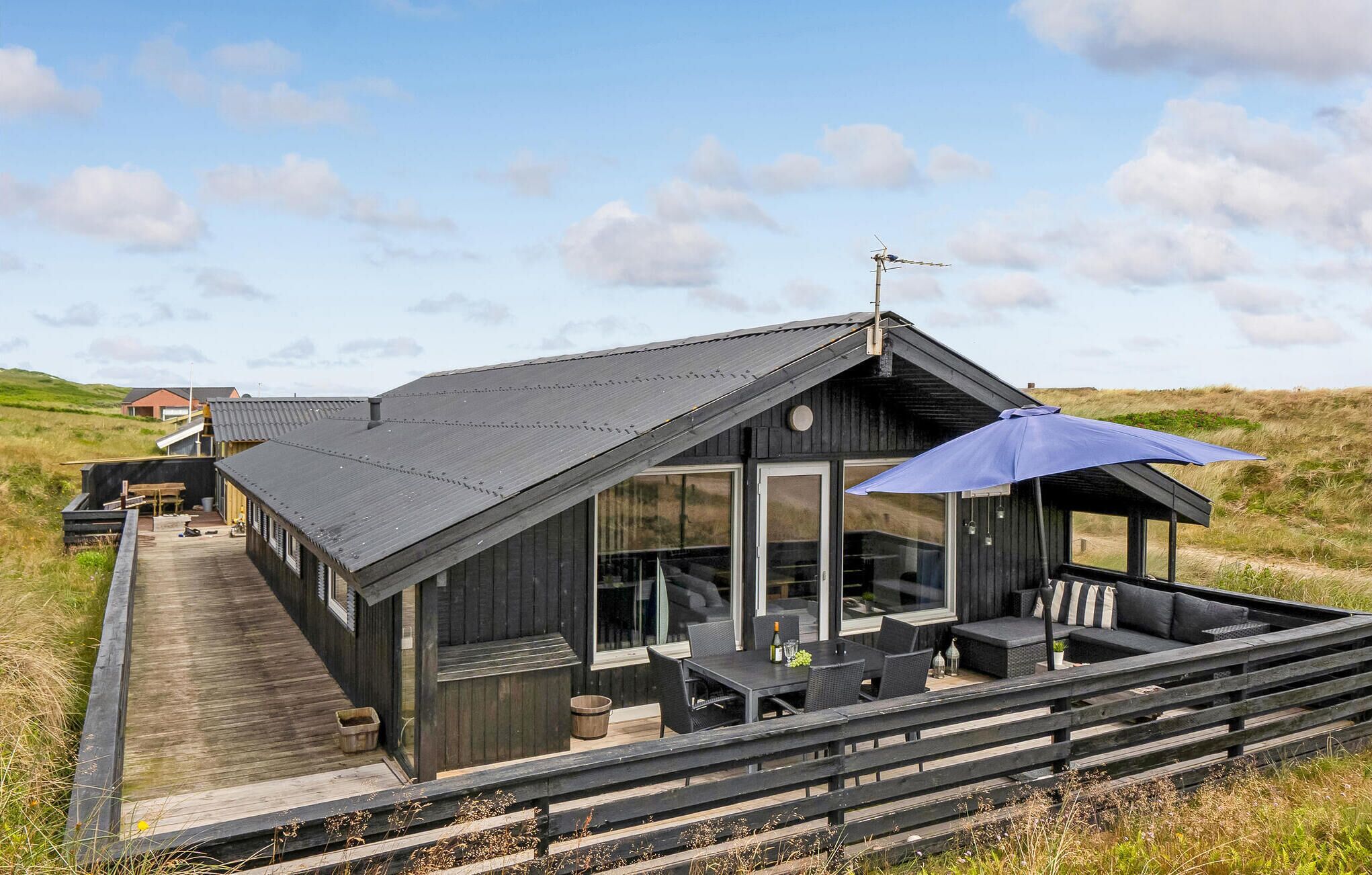 Une cabane moderne dotée d’une grande terrasse, d’un espace salon extérieur et offrant une vue sur le paysage environnant.