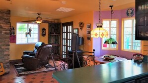 A cozy living room with a fireplace, leather chairs, and a dining area with a green table.