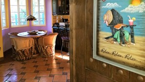 A cozy kitchen with a rustic wooden door, a dining area with a table and chairs, and a wall clock.