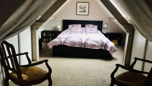 A bedroom with a bed, two chairs, a nightstand, a lamp, and a framed picture on the wall. - Villa 6 persons, 100 m from the sea (Saint-Martin de Bréhal)
