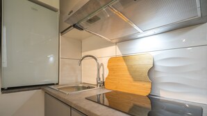 Een moderne keuken met een roestvrijstalen spoelbak, een houten snijplank en een ingebouwde oven.