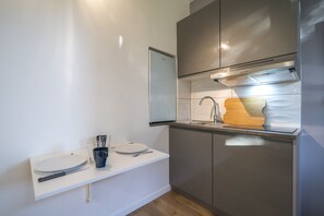 A modern kitchen with a white countertop, stainless steel appliances, and a wooden cutting board.