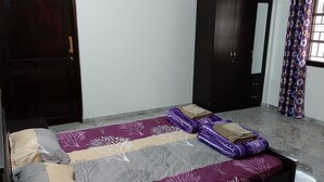 Un dormitorio con cama, armario y ventana con cortinas.