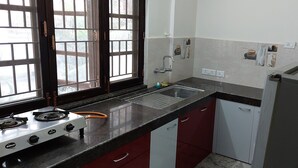 Una cocina con estufa a gas, lavamanos y refrigerador.